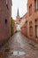 Brick walls street in Bruges with a church tower in the background