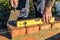 Bricklayer checks the horizontal level of brick masonry wall with a bubble level