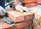 Bricklayer hands in masonry gloves with trowel laying bricks house wall