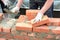 Bricklayer hands in masonry gloves and trowels bricklaying house wall. Building contractors bricklaying house wall,  masonry