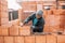 Bricklayer industrial worker installing brick masonry on exterior wall