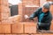 Bricklayer industrial worker installing brick masonry on exterior wall with trowel putty knife