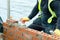 Bricklayer laying bricks on mortar on new residential house construction