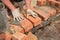 A bricklayer is laying the first row of bricks on a concrete foundation or footing above a damp proof course, a layer of