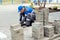 Bricklayer lays paving slabs outside. Working man performs landscaping. Builder lays out sidewalk with stone blocks.