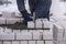 A bricklayer levels bricks in cement, a worker knocks on blocks with a hammer.