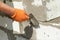 Bricklayer man worker in orange gloves installing block with trowel.