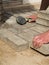 Bricklayer places concrete paving stone blocks for building up a patio hammer tool