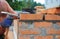 Bricklayer Using a Bricklaying Hammer to Build New Red Brick Wall Outdoor. Bricklaying Basics Masonry Techniques.