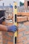 Bricklayer Using a building levell to Check New Red Brick Wall Outdoor. Bricklaying Basics Masonry Techniques