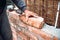 Bricklayer worker installing brick masonry on exterior wall with hands and tools