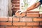 Bricklayer worker placing bricks on cement while building exterior walls, industry details