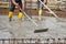 Bricklayers who level the freshly poured concrete to lay the foundations of a building