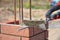 Bricklaying closeup. Bricklayer hand holding a putty knife and building a brick fence column.