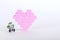 The bricks of the plastic constructor in the form of pink heart whith little robot. White background.