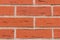 Brickwork rectangular red stones cracks with cement gray lines parallel row natural wall close-up grunge background