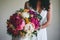 Bridal bouquet with lush bright scarlet peonies and green leaves.