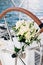 Bridal bouquet of white peonies, freesia, boxwood branches and white ribbons on the sailboat wheel