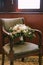 Bridal bouquet of white peonies, roses, veronica and branches of eucalypt tree on a wooden armchair with green satin