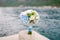 Bridal bouquet of white roses, eucalyptus tree branches, blue hortensias, green asters and blue ribbons on the pier by
