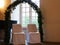 Bridal couple chairs under trellis arch at window and piano