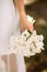 Bridal wedding bouquet with white flowers. Bride in white dress holding classic callas bouquet on brown background