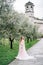 Bride in a beautiful dress with a pensive look stands on the path in the olive grove. Lake Como. Italy