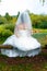 Bride in beautiful wedding dress with long veil sitting by a fish pond in nature.