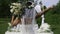 The bride from behind holding a bouquet in one hand while the other is raised in the air in symbol of peace or victory.