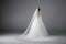 A bride from behind in a white full wedding long dress in a studio, isolated on gray background