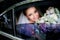 Bride with blue eyes holds tender wedding bouquet sitting in the car