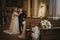 Bride and bridegroom in the church with a flower bouquet in the foreground