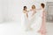 Bride and bridesmaid drinking champagne, enjoying before wedding in hotel room. White loft room