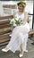 A bride with a budget and a flower wreath on her head sits on a boat and smiles at the camera