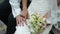 Bride caresses groom\'s hand near a bridal bouquet