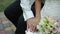 Bride caresses groom\'s hand near a bridal bouquet