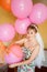 Bride in casual clothes with veil among pink balloons, preparing for wedding.