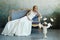 Bride in a chic long dress lying on the sofa couch. White wedding dress on the bride`s body. Beautiful light dress with a long he