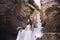 The bride in a chic wedding dress is standing on a background of a glacier in a mountain range