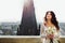 Bride daydreams with lily bouquet in her arms with cityscape on
