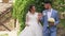 Bride in follows fiance holding groom hand against orange brick wall slow motion