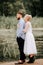 The bride gently hugs the groom from behind on the shoreline. Beautiful newlyweds on the background of the river