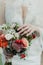 The bride gently touches a beautiful wedding bouquet, which consists of white roses and lush green twigs