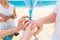 Bride giving an engagement ring to her groom under the arch decorated with flowers on the sandy beach. Wedding ceremony on