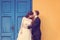 Bride and groom against yellow wall and blue door