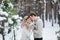 Bride and groom in beige knitted pullovers in snowy forest. Newlyweds is touching foreheads. Winter wedding