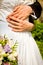 Bride and groom with bunch of flowers. Hands of bride and groom with rings.