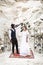 Bride and groom in canyon outdoors. wedding ceremony. boho wedding arch. African man and Caucasian woman in boho wear