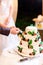 Bride and groom cutting wedding cake decorated with fig fruit, fresh blackberry and green leaves. Couple Hands Cutting