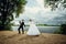 The bride and groom dance their merry wedding dance on the shore of the pond